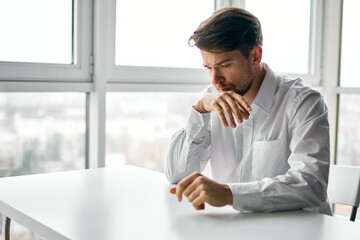 a man in a white shirt sits at a table office dissatisfaction