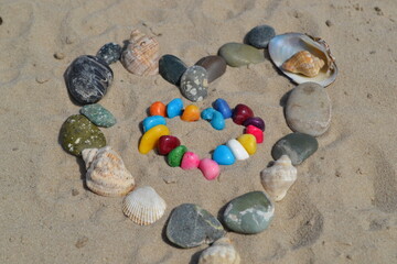 The figure of a heart on the sand of stones and shells.