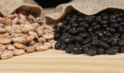 Fototapeta premium Dried Pinto Beans and Black Beans in Burlap Bag on Wooden Background