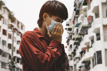 Young asia man can't breathe because wearing the respiratory protection mask against air pollution and dust particles exceed the safety limits.environmental, ecology concept.headache.