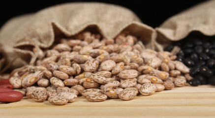 Burlap Bag of Dried Pinto Beans Spilled on Wooden Table