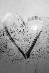 symbol of beautiful heart with the sun inside painted on misted glass, moonlight, texture of frost and water drops