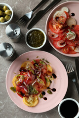 Concept of tasty food with tomato carpaccio on gray textured table