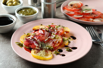 Concept of tasty food with tomato carpaccio on gray textured table