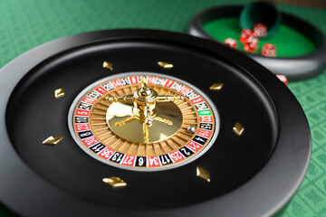 Casino. Gambling games theme.  Roulette wheel, dice and poker chips on the casino felt green table.