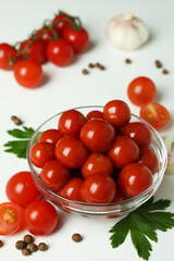 Bowl with pickled tomatoes and ingredients on white background