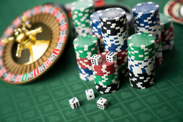 Casino. Gambling games theme.  Roulette wheel, dice and poker chips on the casino felt green table.