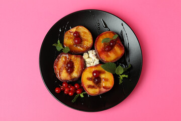 Plate with tasty grilled peach on pink background