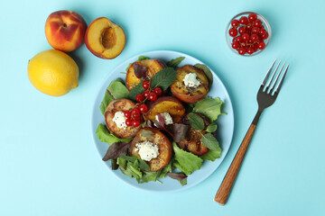 Plate of salad with grilled peach on blue background