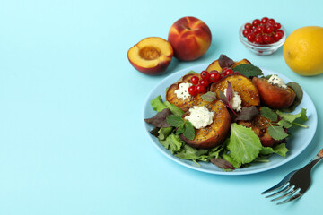 Plate of salad with grilled peach on blue background