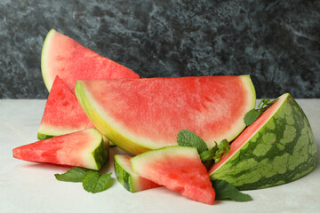 Watermelon slices and mint leaves on white textured table