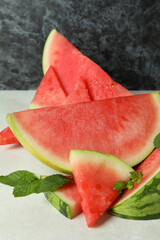 Watermelon slices and mint leaves on white textured table