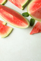 Watermelon slices and mint leaves on white textured table