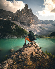 hiker man with backpack at mountain lake lago di sorapis in the dolomites during summer