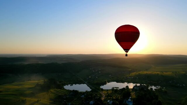 A balloon flies in the middle of the horizon at sunset. Picturesque picture of a balloon flying in the sun. Beautiful landscape: dusk, balloon, lake and sunset