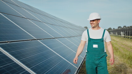 Engineer is checking the operation of sun and cleanliness of photovoltaic solar panels. Concept renewable energy. Caucasian man in hard helmet examining object solar panels. Concept of green energy