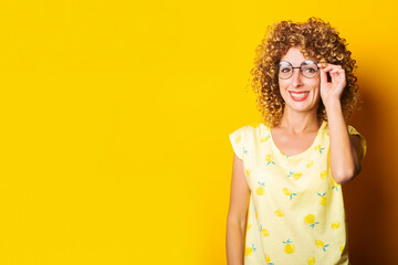 smiling young woman in round transparent glasses on a yellow background