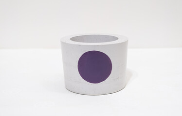 Colorful, handmade cactus pot on a white background with fine holes in the texture and painted purple dot