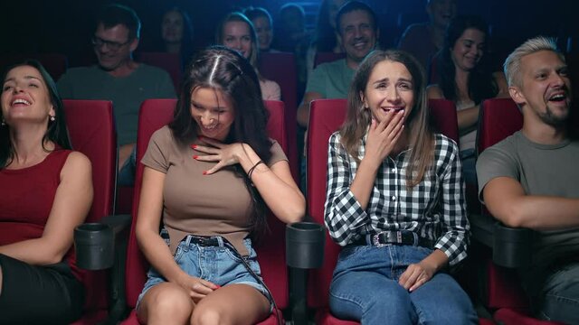 Two female friends laughing having positive emotion at comedian movie sitting on armchair row