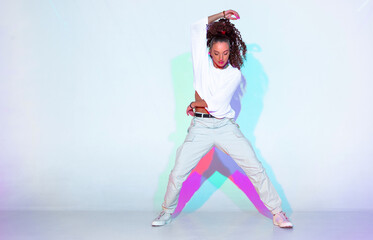 Dancing mixed race young girl in colourful studio light. Stylish female dancer performer show hip hop dance. Copy space