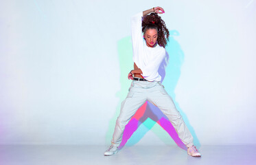 Dancing mixed race young girl in colourful studio light. Stylish female dancer performer show hip...