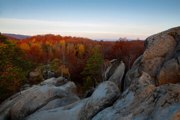Fantastically beautiful view of the autumn beech forest and rocks in the morning light.