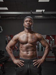 Fototapeta na wymiar Brutal muscular athletic african american guy with naked torso posing on training in gym. Visceral fat on belly