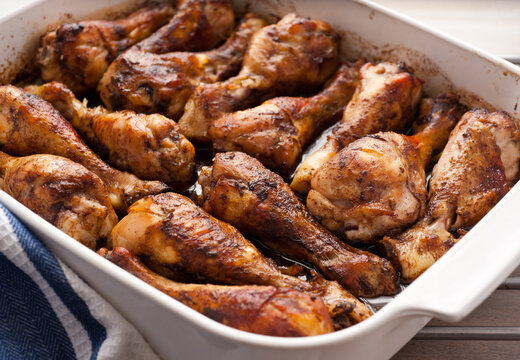 Chicken drumsticks roasted in baking dish with honey soy marinade, close up