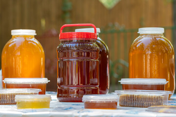 On the table are glass jars and plastic containers filled with Bashkir bee honey and ready to be sold at the honey fair.