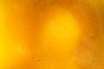 The golden textured surface of liquid bee honey with reflections of light. Delicious and healthy food.