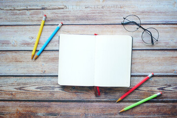high angle view of open diary and colorful pencils on table 