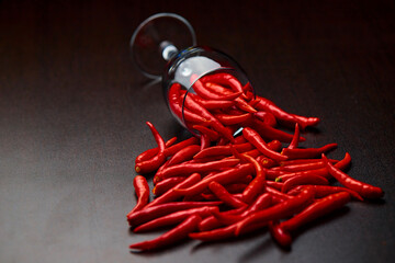 The poured red chili peppers with The overturned glass cup of red chili peppers