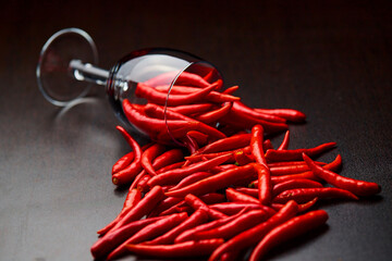 The poured red chili peppers with The overturned glass cup of red chili peppers