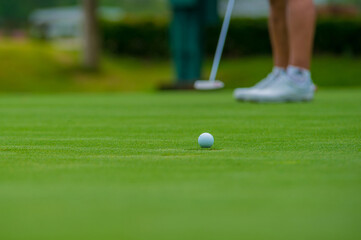 A white golf ball putter goes to the hole on the green grass