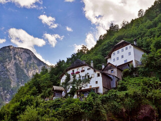 Fototapeta na wymiar Two big white houses in the middle of a green mountain in Hallstatt, Austria.
