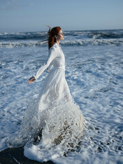 Fototapeta na wymiar Woman in white dress walking along the coast of the ocean Freedom fashion