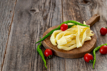 Chechil cheese or string cheese on wood floor. Cheese on serving board. Copy space