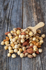 Mixed nuts on wood floor. Organic and fresh nuts. Wooden spoon on top of nuts. close up