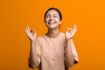 Portrait of young adult successful indian woman meditating zen like with ok sign mudra gesture.