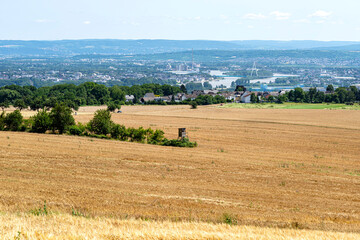 Obraz premium The stubble field in the summer in the background, the river between the buildings and the bridge, aerial view.