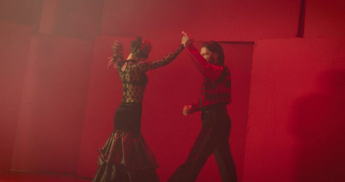 4K Beautiful couple dancing latin dance . Professional dancers dancing flamenco, rumba or salsa on red background. Pair in spanish dress performs dance movement. Shot ARRI ALEXA Camera in Slow Motion 