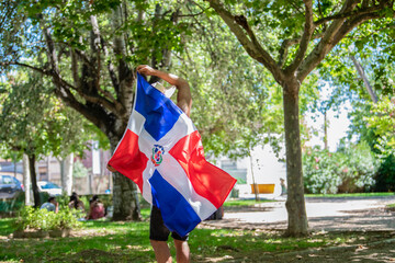 Latino man holding a Dominican Republic flag outdoors