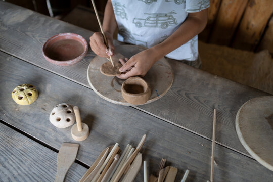 Boy put signature on his work in pottery workshop