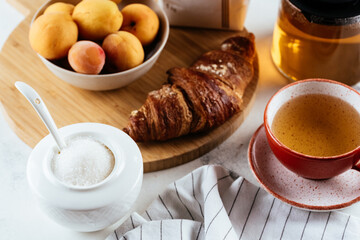white sugar in a ceramic bowl, croissant and tea on a marble bac