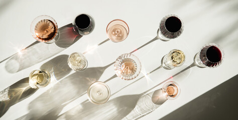 Glasses of red, white and rose wine on white with shades, top view