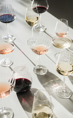 Glasses of red, rose and white wine on white background with shades