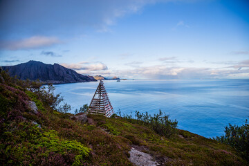 Scenic view mountains, sea and wooden pyramid on the trail from Nosfjord till Nesland village...