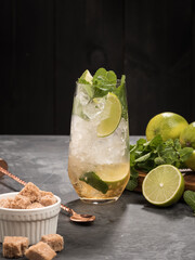 Refreshing mint cocktail mojito with rum and lime, cold drink or beverage with ice on black background