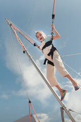 Jumping rubber band in an amusement park. Girl jumping on a trampoline ride with rubber belay ropes