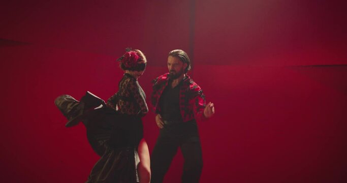 4K Beautiful couple dancing latin dance . Professional dancers dancing flamenco, rumba or salsa on red background. Pair in spanish dress performs dance movement. Shot ARRI ALEXA Camera in Slow Motion 